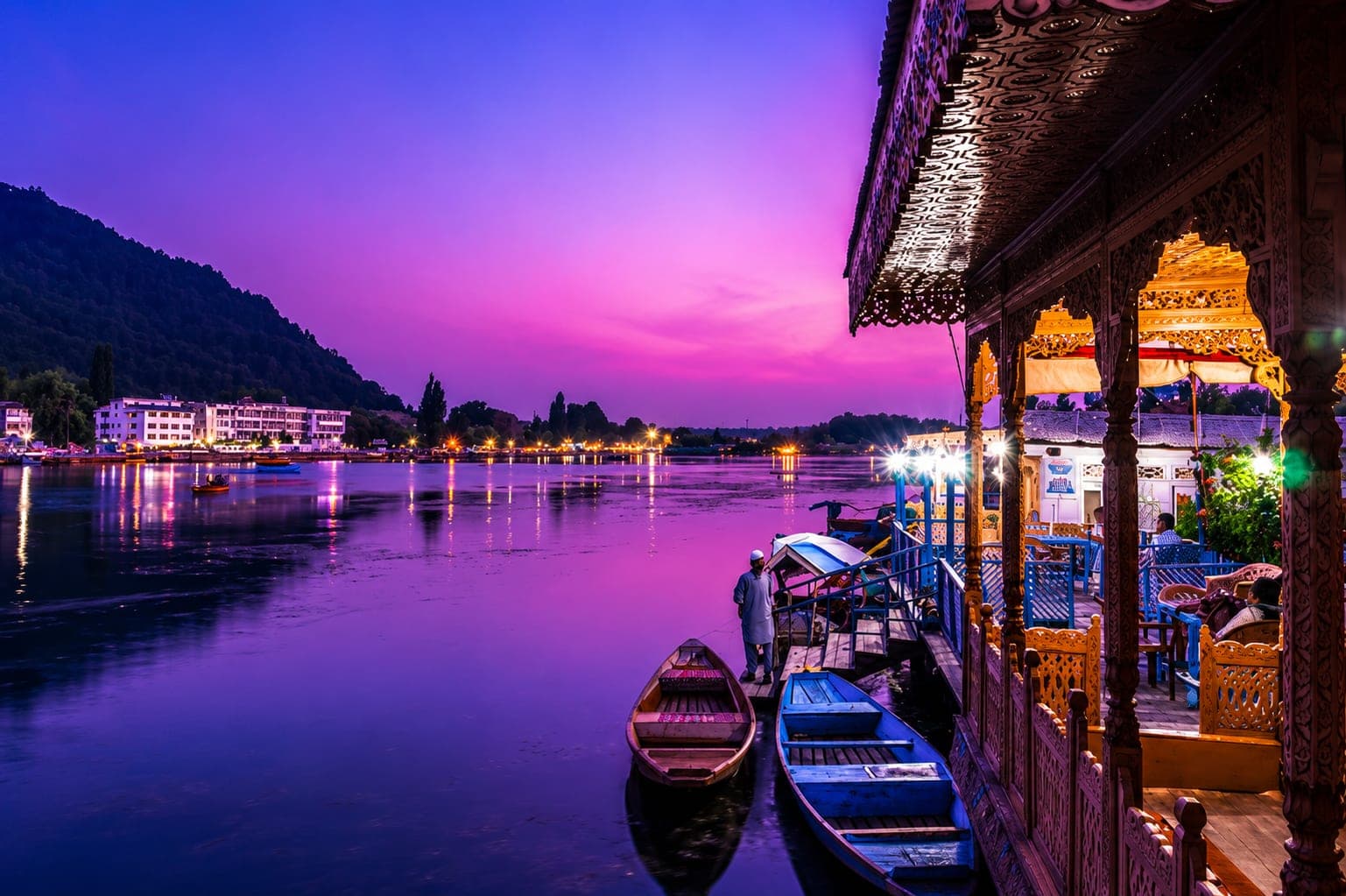 A traditional houseboat lit up at dusk on Dal Lake, Srinagar
