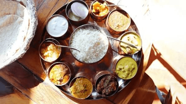A traditional Himachali thali with dal, sabzi and rice served in individual copper bowls